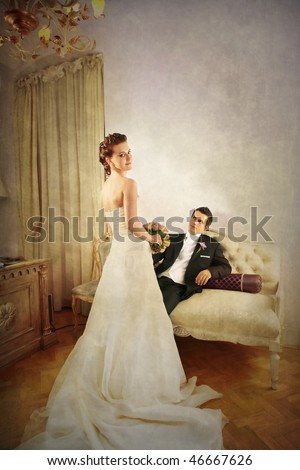 Full length of beautiful bride and groom in luxurious with vintage look interior and dress seen from the rear side