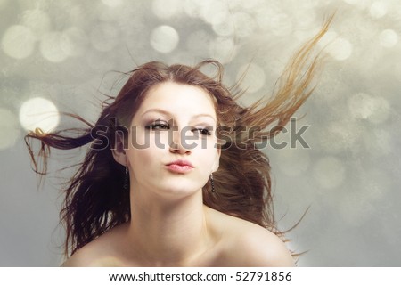 Attractive teenage girl model with hair blowing in the wind isolated on green bokeh background