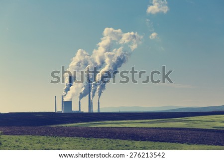 Coal power plant with steam and smoke against blue sky
