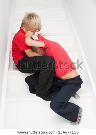 Siblings fighting on the stairs in the home.