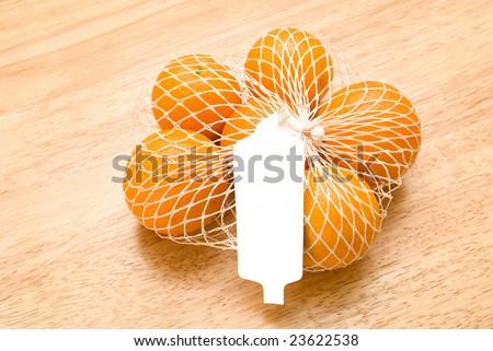 Oranges in a white netted bag with blank price tag.