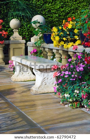 Stylish concrete bench surrounded by flowers on a patio
