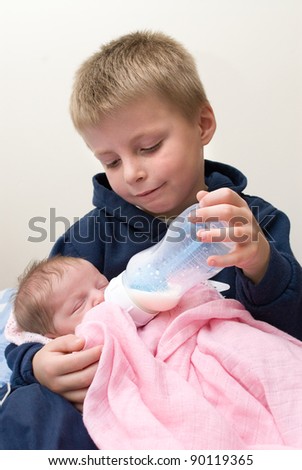 Six year old sibling feeding his newborn baby sister.