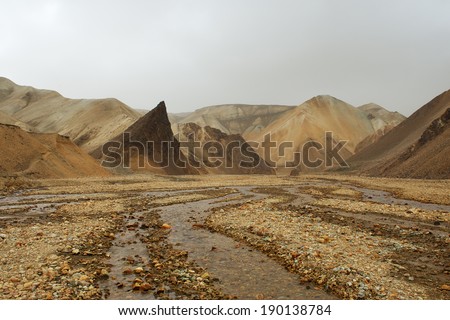 Lifeless orange rocks and a river during the sand storm, Landmannalaugar, Iceland