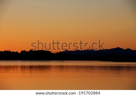 Trees and houses silhouette reflecting in the water at the sunset, Iceland