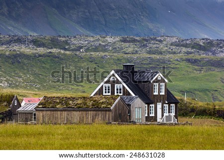 Old wooden brown farm house with moss and grass on the roof on a cloudy day, Arnarstapi, West Iceland