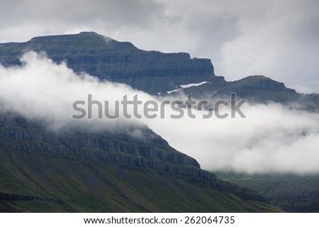 Rocky mountains covered with green moss and clouds in Westfjords, Iceland