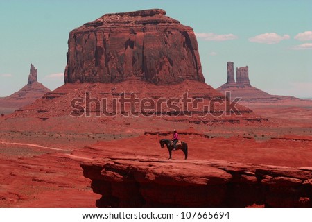 A lone indian rider sits on his horse in front of the famous rock formations of Monument Valley in Arizona,