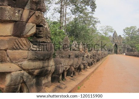A  row of temple guardians holds an enormous snake to keep evil spirits away from this wat at Angkor in the jungle of Cambodia.