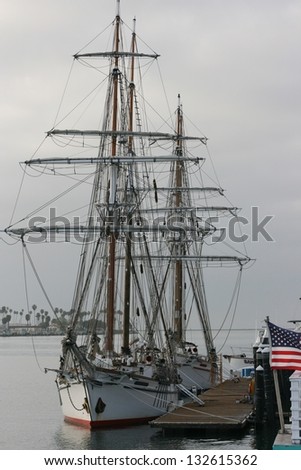 A fully rigged barketine sailing ship gets ready to put to sea.