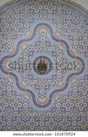 Hand painted tiles surround a brass animal head that is a fountain in Marrakesh, Morocco
