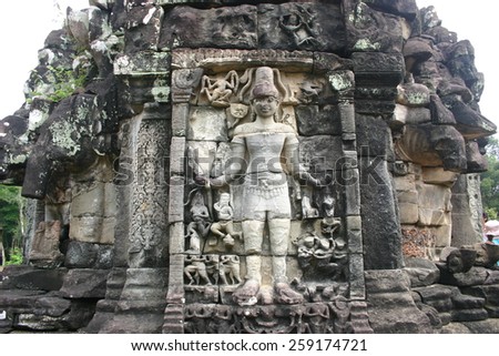 An ancient deity stands watch on a stone carved temple at Angkor Wat in the Cambodian jungle,