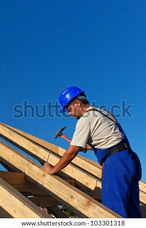 Carpenter building roof structure - driving in large nail