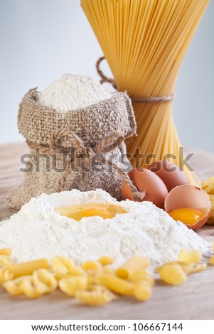 Ingredients for making pasta - flour and eggs on wooden table surface