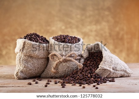 Roasted coffee beans in burlap bags on old table
