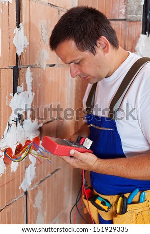 Electrician working inside new building measuring and checking wires - closeup