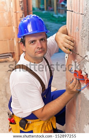 Electrician installing wires in a new brick building