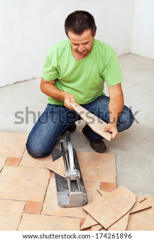 Worker cutting and installing ceramic floor tiles