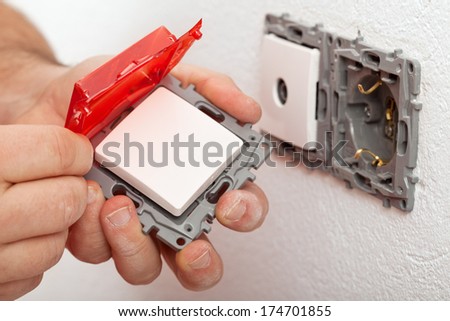 Changing or installing an electrical switch - closeup of an electrician\'s hands.