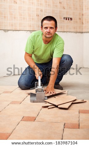 Man cutting ceramic floor tiles - looking in the camera