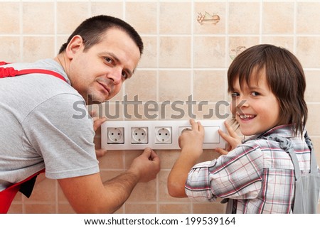 Father and son installing electrical wall fixtures together - working around the house