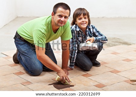 Father and son testing the color of joint on ceramic floor tiling