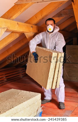 Man laying thermal insulation layer under the roof - carry the mineral wool panels