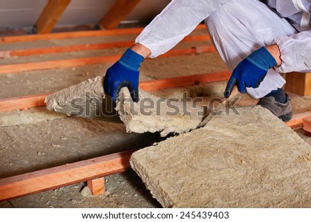 Installing thermal insulation layer - closeup on hands cutting rock wool