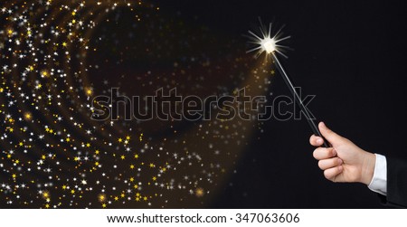Magician hand conjuring sparks on black background - copy space with magic