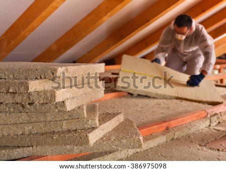 Thermal insulation of a building - mineral wool panels stack with man measuring in the background