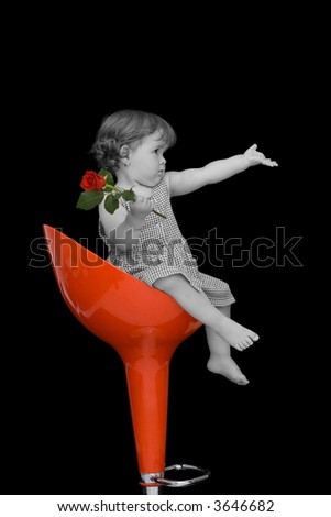 Baby girl with a rose sitting on a red swivel chair - vintage effect with selective desaturation - isolated on black