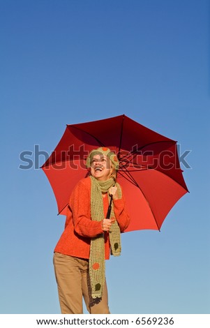 Happy autumn woman with red umbrella under clear blue sky - warm afternoon light