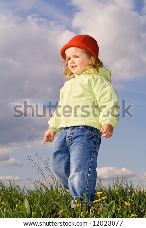 Little girl on the early spring field against cloudy blue skies - slight motion blur on the left hand