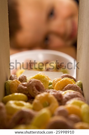 Boy eagerly waiting for the breakfast cereals to be poured out of the box