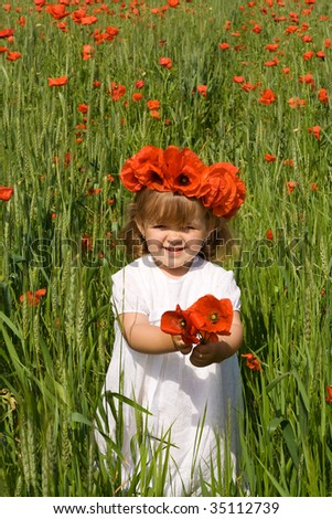 Little girl with white dress on the green wheat field with poppies wearing a flower crown
