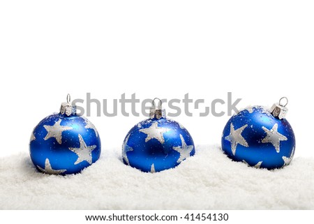 Three blue christmas balls with silver star motives in the snow - isolated