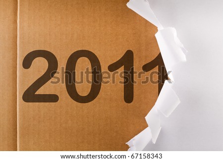 Torn wrapping paper revealing 2011 written on brown cardboard layer - new year concept