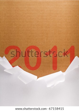 Torn packaging paper revealing 2011 written on brown cardboard box - brand new year concept