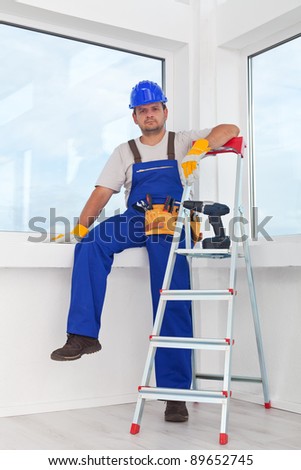 Handyman or worker resting after work leaning on the windowsill