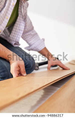 Man laying laminate flooring - closeup on fitting the next piece