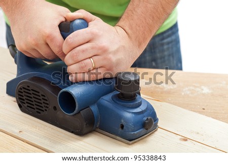 Construction worker hands and power tool - planing a piece of wood