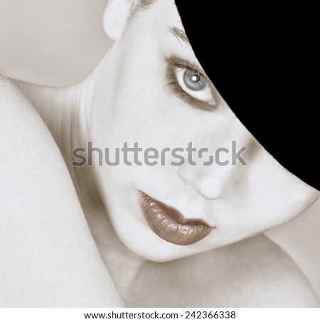 Closeup of a young woman with bare shoulders wearing a bowler hat pulled down over one eye. Desaturated high key image in square format. Only lips and eye have a hint of color.