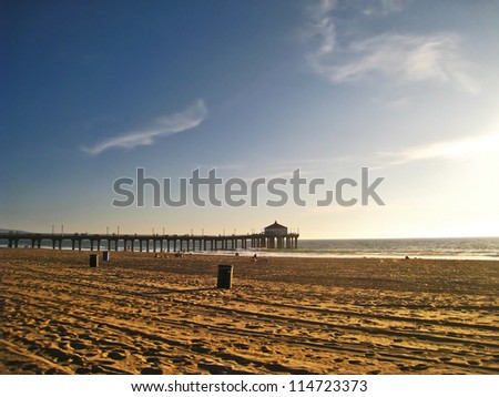Ocean pier and boardwalk with sandy beach at sunset