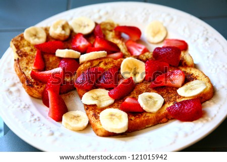 Fresh made french toast with bananas and strawberries on white plate