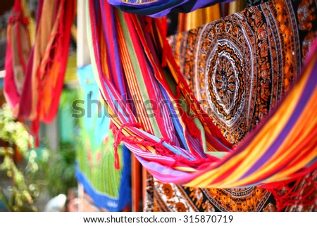 Ethnic blankets and hammocks with aztec various pattern hanging in street market