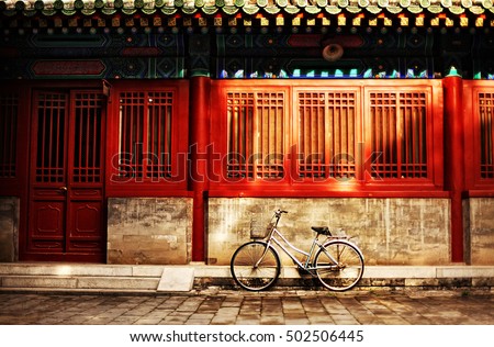 One bicycle in front of oriental red building in urban Asia city on street sidewalk on sunny afternoon