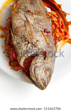 Cooked Dorado fish with vegetable on a white plate