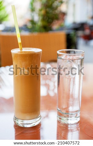 Frappe with a glass of water on cafe table. Crete, Greece