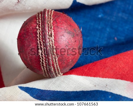 A used red leather cricket ball with an old British union jack flag background