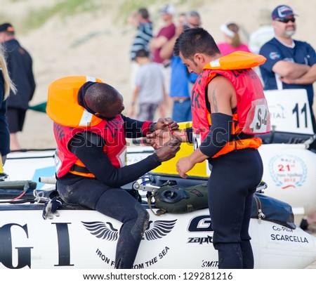STILBAAI,SOUTH AFRICA -DEC. 30: A team mate attaches a cord onto the wrist of his companion during the Trans Agulhas Challenge on Dec. 30, 2012 in Stilbaai.